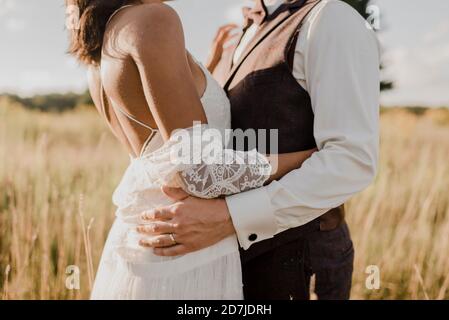 Midsection of couple embracing each other at field on sunny day Stock Photo