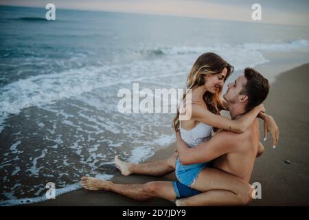 Young couple doing romance while sitting on beach Stock Photo
