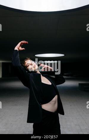 Trans young man listening music and dancing in illuminated basement Stock Photo