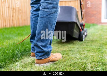 Man standing with lawn mower at backyard Stock Photo