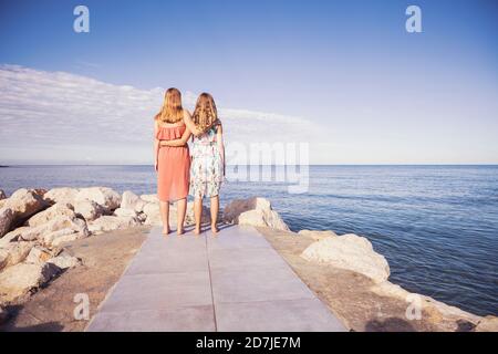 Friends looking at view with arms around on sunny day Stock Photo
