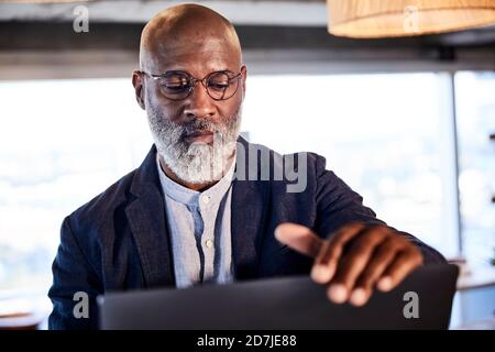 Serious mature man working on laptop sitting at home Stock Photo