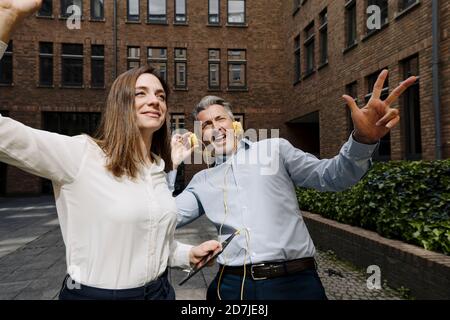 Business people dancing and listening music against building Stock Photo