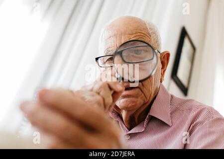 Retired senior male looking through magnifying glass at fossil Stock Photo