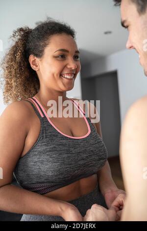 Woman wearing sports clothing looking at man while standing at home Stock Photo