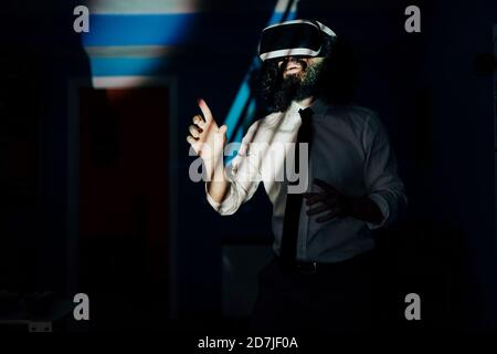 Man using virtual reality glasses while standing at home during pandemic Stock Photo