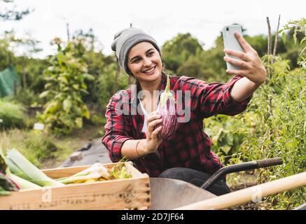 Young woman taking selfie with eggplant in vegetable garden Stock Photo