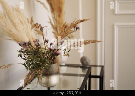 Cute little dried flowers in small glass vase in the living room. Stock Photo