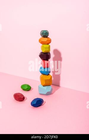 Multi colored wooden blocks stack against pink background Stock Photo