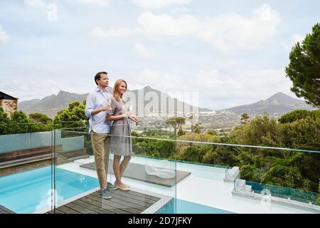 Couple holding wine glass while standing in balcony Stock Photo