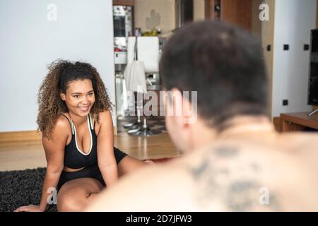 Man giving guidance to woman while exercising at home Stock Photo