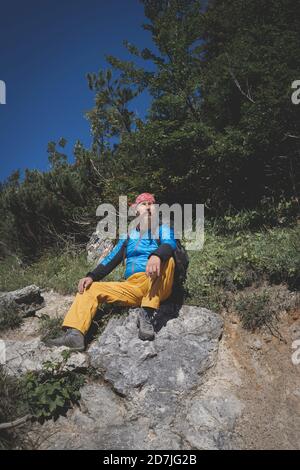 Male hiker sitting on mountain during sunny day, Otscher, Austria Stock Photo