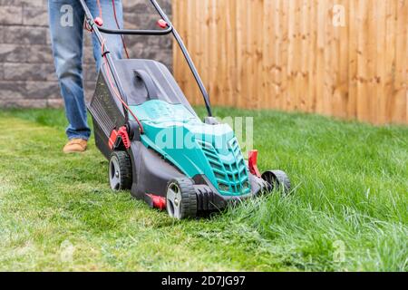 Mid adult man standing with lawn mower at backyard Stock Photo