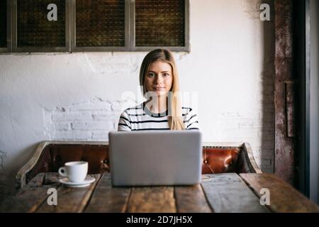Woman using laptop while sitting in cafe Stock Photo