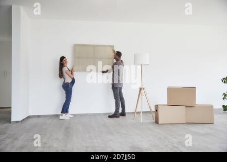 Couple hanging frame on wall at new home Stock Photo
