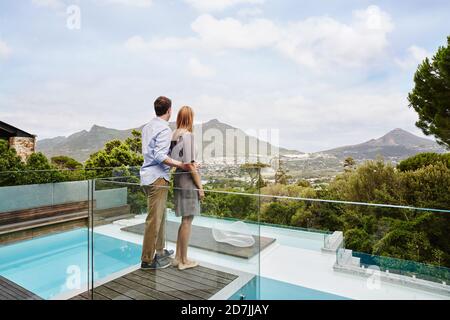 Heterosexual couple standing while looking at view from balcony of modern house Stock Photo