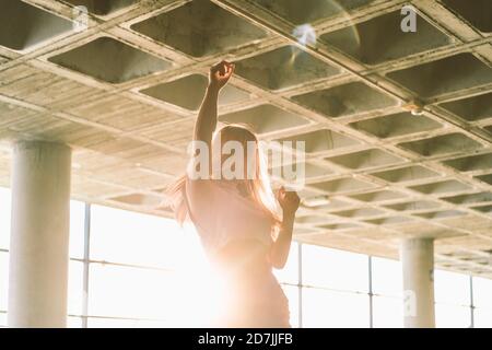 Back lit young woman dancing at parking garage Stock Photo