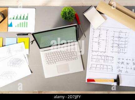 Laptop and various architectural tools, blueprints and plans lying on desk in studio Stock Photo