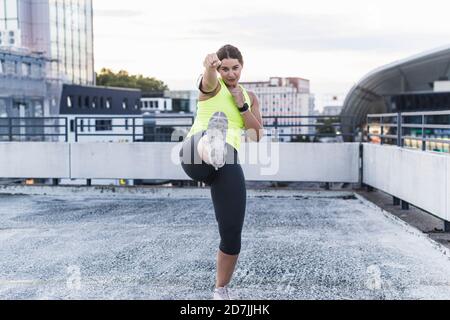 Young woman boxing and kicking on terrace at sunset Stock Photo