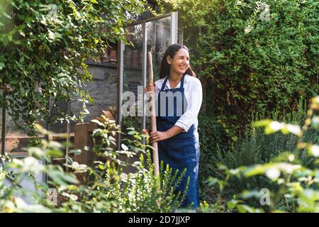 Smiling mature woman looking away while standing in back yard Stock Photo