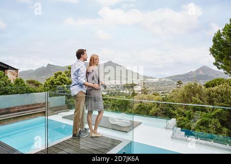 Couple standing while looking at view from balcony of modern house Stock Photo