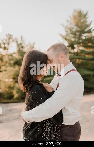Couple embracing while nuzzling nose with each other in forest Stock Photo