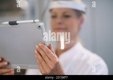 Close-up of female scientist wearing protective face shield while using digital tablet at laboratory Stock Photo