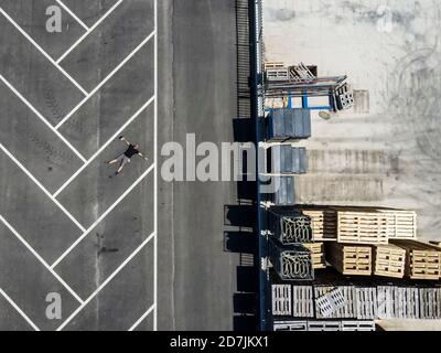 Drone view of man lying on back in empty parking lot Stock Photo