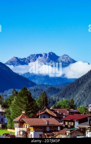 Austria, Tyrol, Ehrwald, Mountain village houses with forested valley and Zugspitze mountain in background Stock Photo