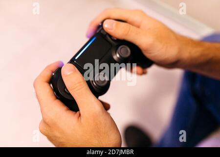 Hands of young man holding controller while playing video game at home Stock Photo