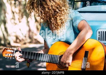 Mature woman with curly hair playing guitar while leaning on motor home Stock Photo