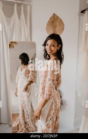 Reflection of bride looking over shoulder while standing at wedding dress shop Stock Photo