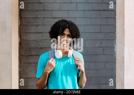 Young man standing with headphone against brick wall Stock Photo
