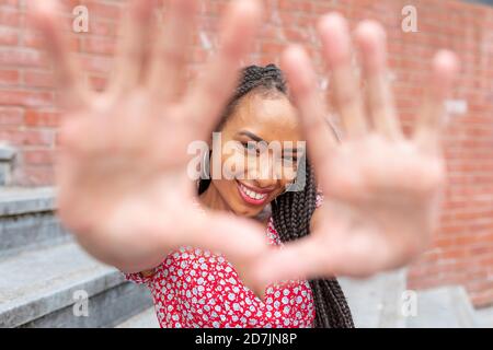 Young woman gesturing stop sign while sitting on staircase in city Stock Photo