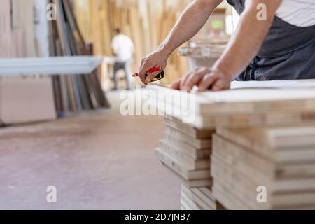 Expertise measuring wood with measure tape while standing at workshop Stock Photo