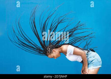 Woman tossing hair against blue wall Stock Photo