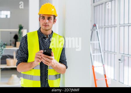 Architect using mobile phone while standing at office under construction Stock Photo