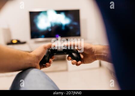 Hands of young male gamer holding controller while playing at home Stock Photo