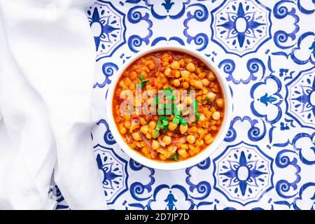 Bowl of vegan stew with chick-peas, red lentils, tomatoes, Spanish onions and mint Stock Photo