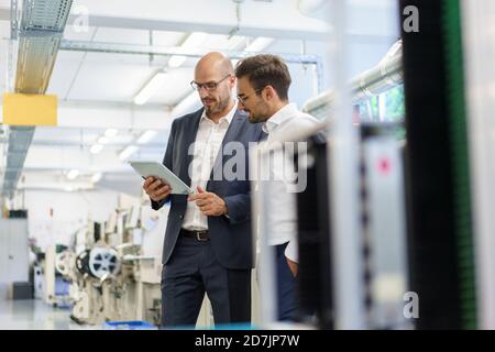 Businessmen discussing over digital tablet while standing at factory Stock Photo