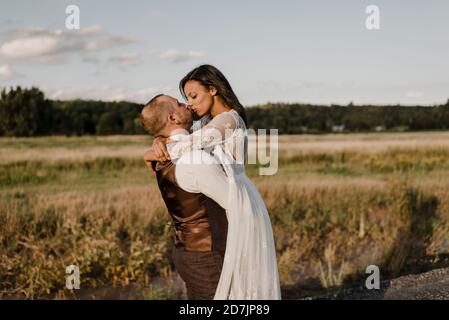 Heterosexual couple kissing while standing at agricultural field Stock Photo
