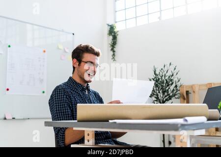 Smiling man working while sitting by desk at office Stock Photo