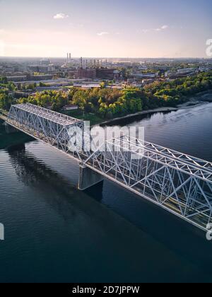 Metallic railway bridge over Volga River by city against sky Stock Photo