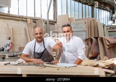 Smiling project manager and coworker standing in factory Stock Photo