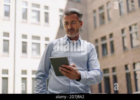 Businessman using digital tablet while standing against building Stock Photo