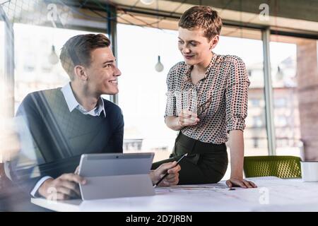 Smiling business partners discussing at desk in office Stock Photo