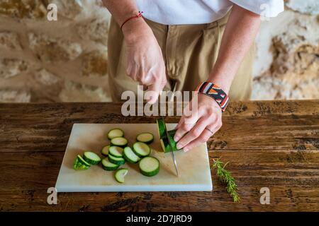 Female dietitian cutting cucumber on marble board at table Stock Photo