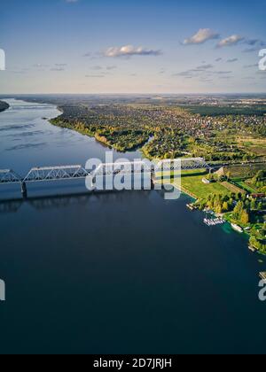 Railway bridge over Volga River in city against sky at sunset seen from above Stock Photo