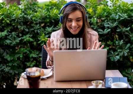 Smiling female entrepreneur video calling through laptop while sitting on terrace at cafe Stock Photo