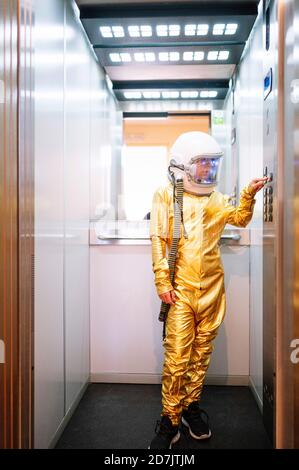 Boy wearing space suit pressing buttons in open elevator Stock Photo